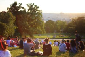 Diverse group relaxing on grassy hill at sunset, with city skyline in background
