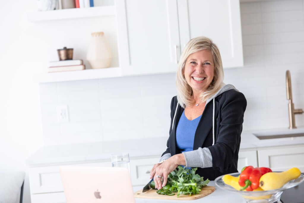 dr. jennifer schwartz, a telehealth weight lsos doctor, slicing vegetables in a bright white kitchen